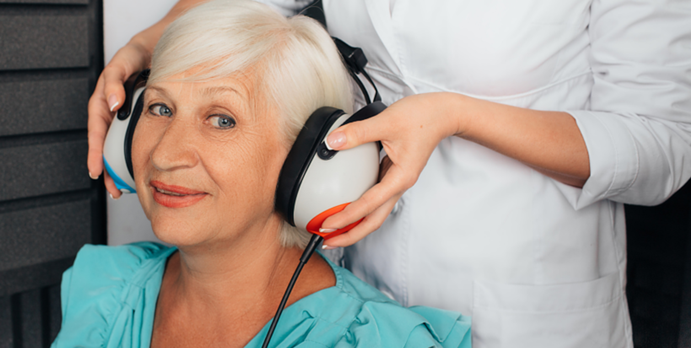 Person in white placing headphones on a woman wearing teal blouse