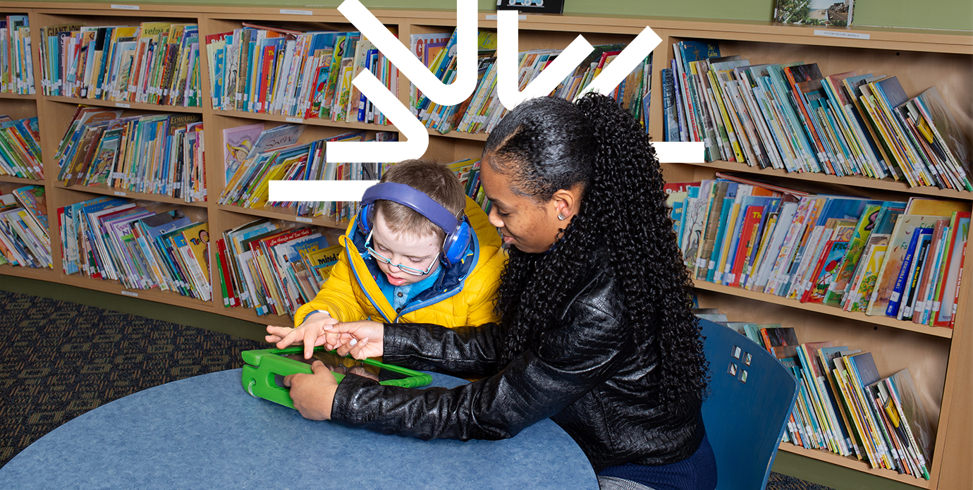 Photo of a person and child reading in a library